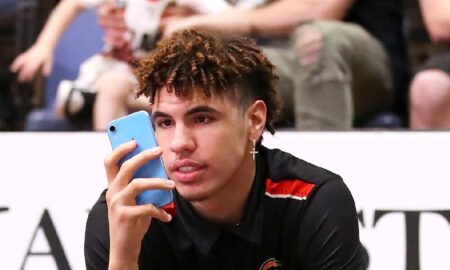 lamelo ball checking his phone at a basketball game
