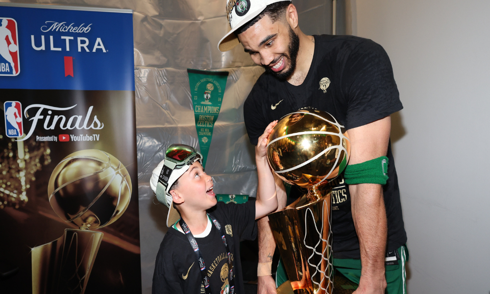 Jayson Tatum and son Deuce exchange a look of euphoria while holding the Larry O'Brien Trophy.