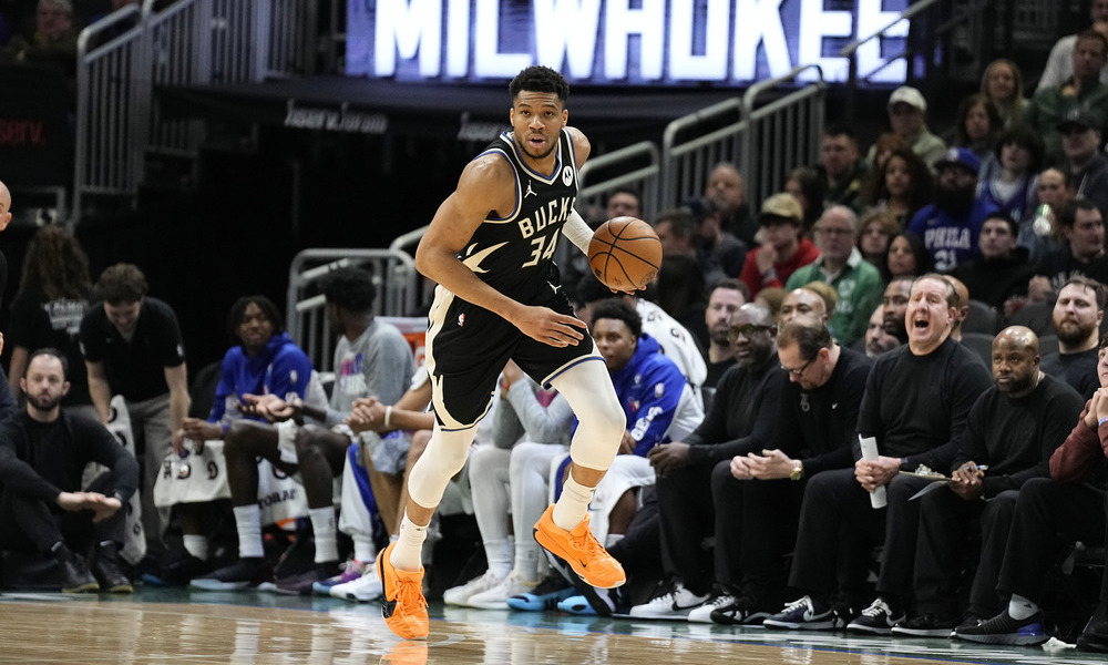 Giannis Antetokounmpo looks up the court as he dribbles the ball down on a fast break.