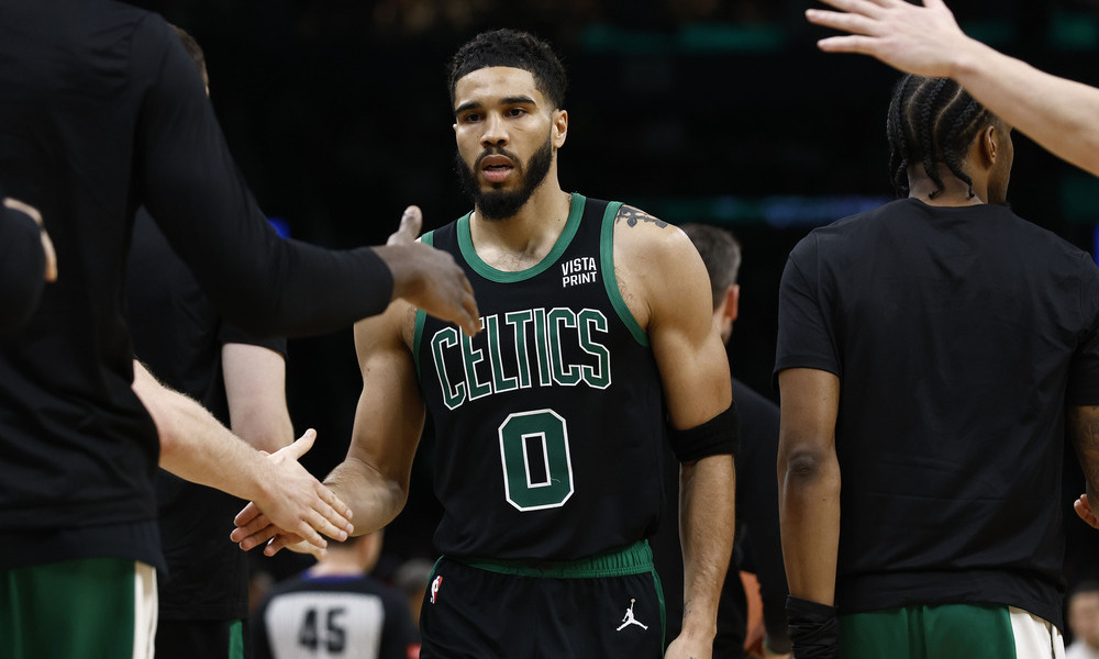 Jayson Tatum high fives his teammates during a stoppage of play.