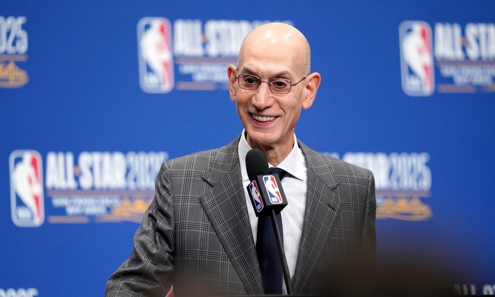 Adam Silver smiling as he addresses reporters during a press conference.