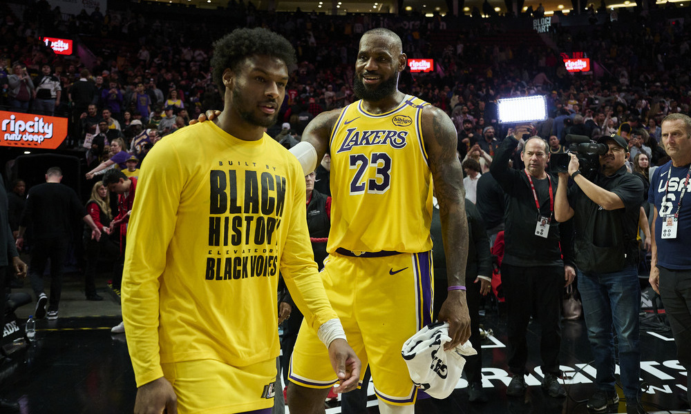 LeBron and Bronny James talk before the start of a game.