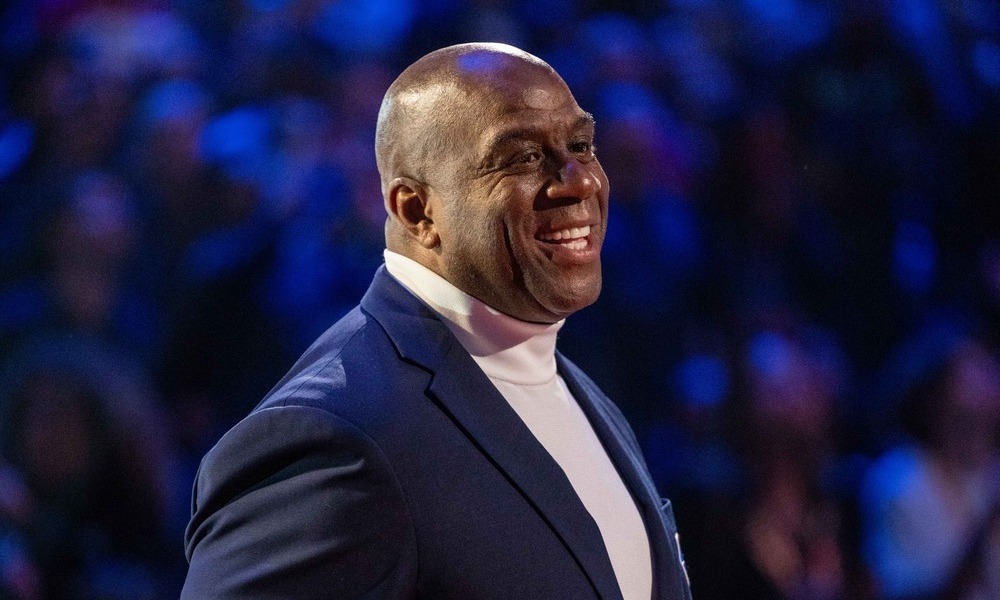 Magic Johnson smiling while he stands on stage.